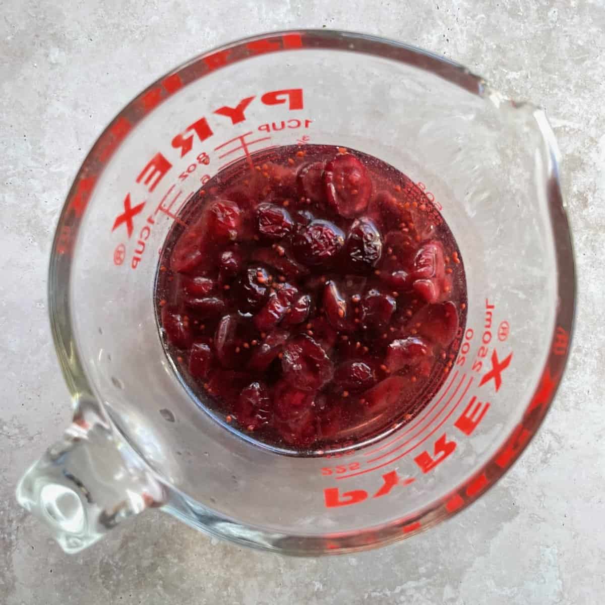 dried cranberries and cranberry seeds in water in a pyrex measuring cup.