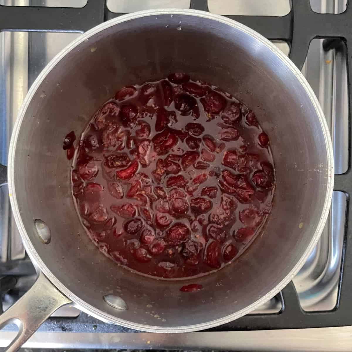 dried cranberries, water, orange zest and other ingredients for cranberry sauce in a pot.