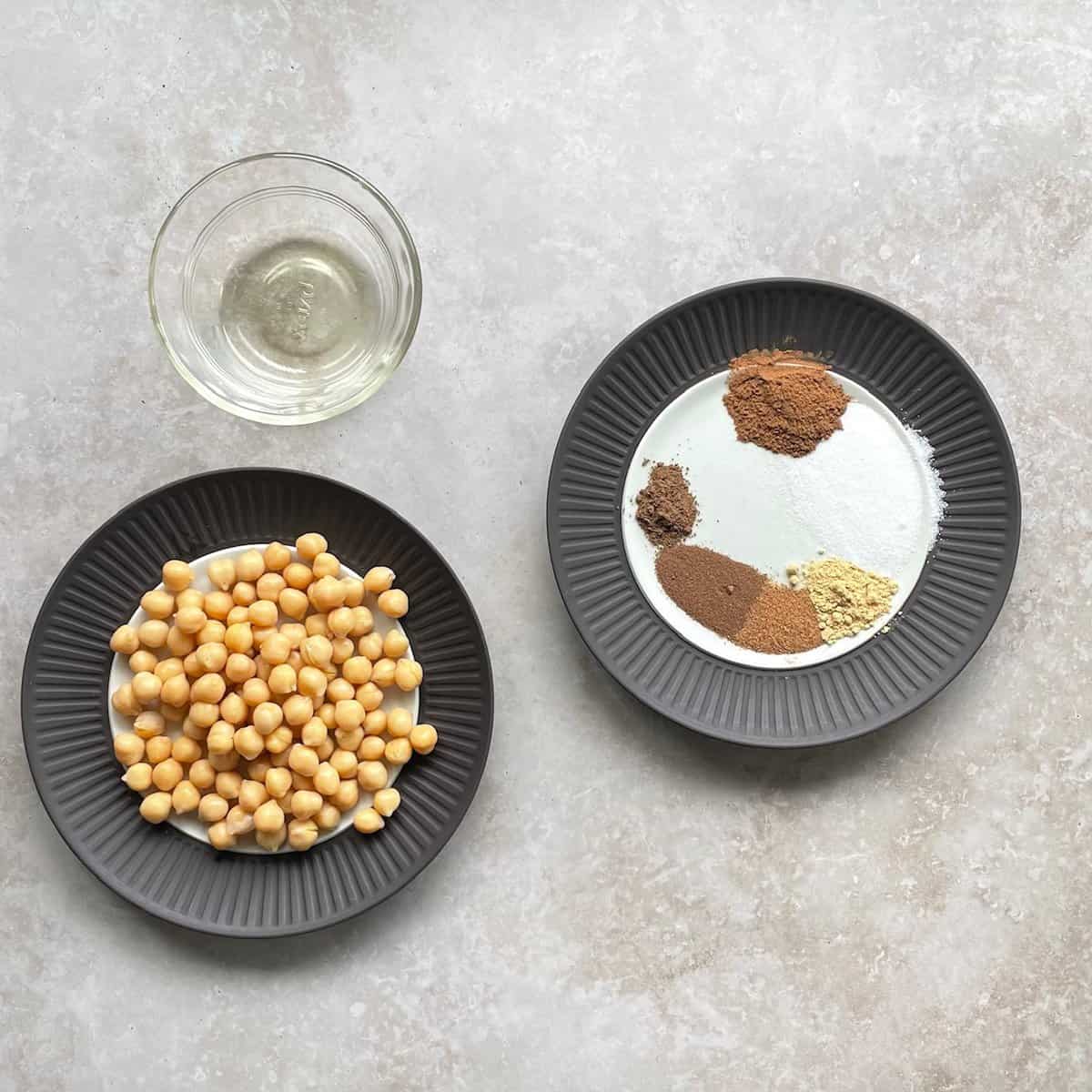 chickpeas, bowl of oil, and plate with different spices on a countertop.