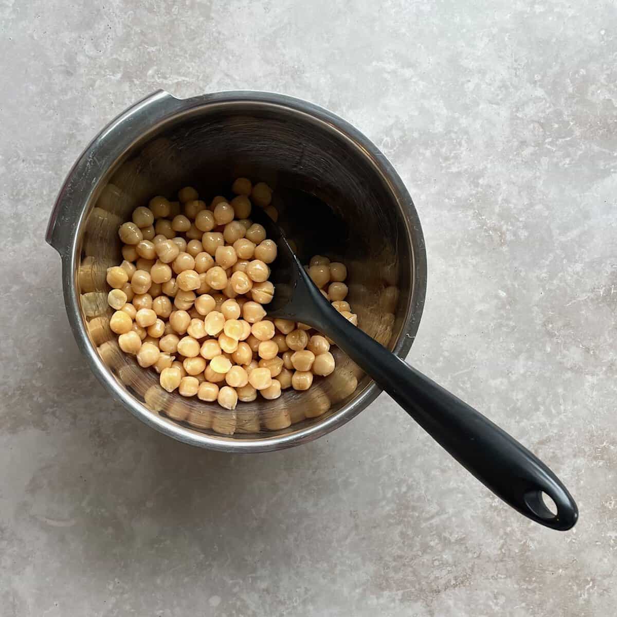 bowl of oil-coated chickpeas and spatula.