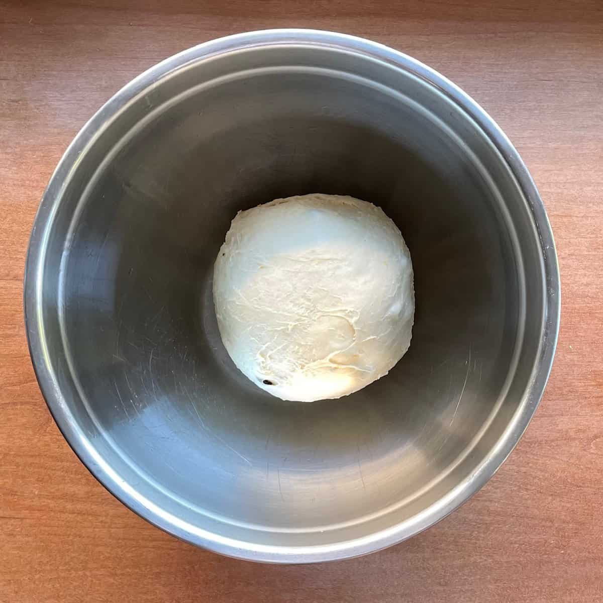 small boule of bread dough in a mixing bowl.