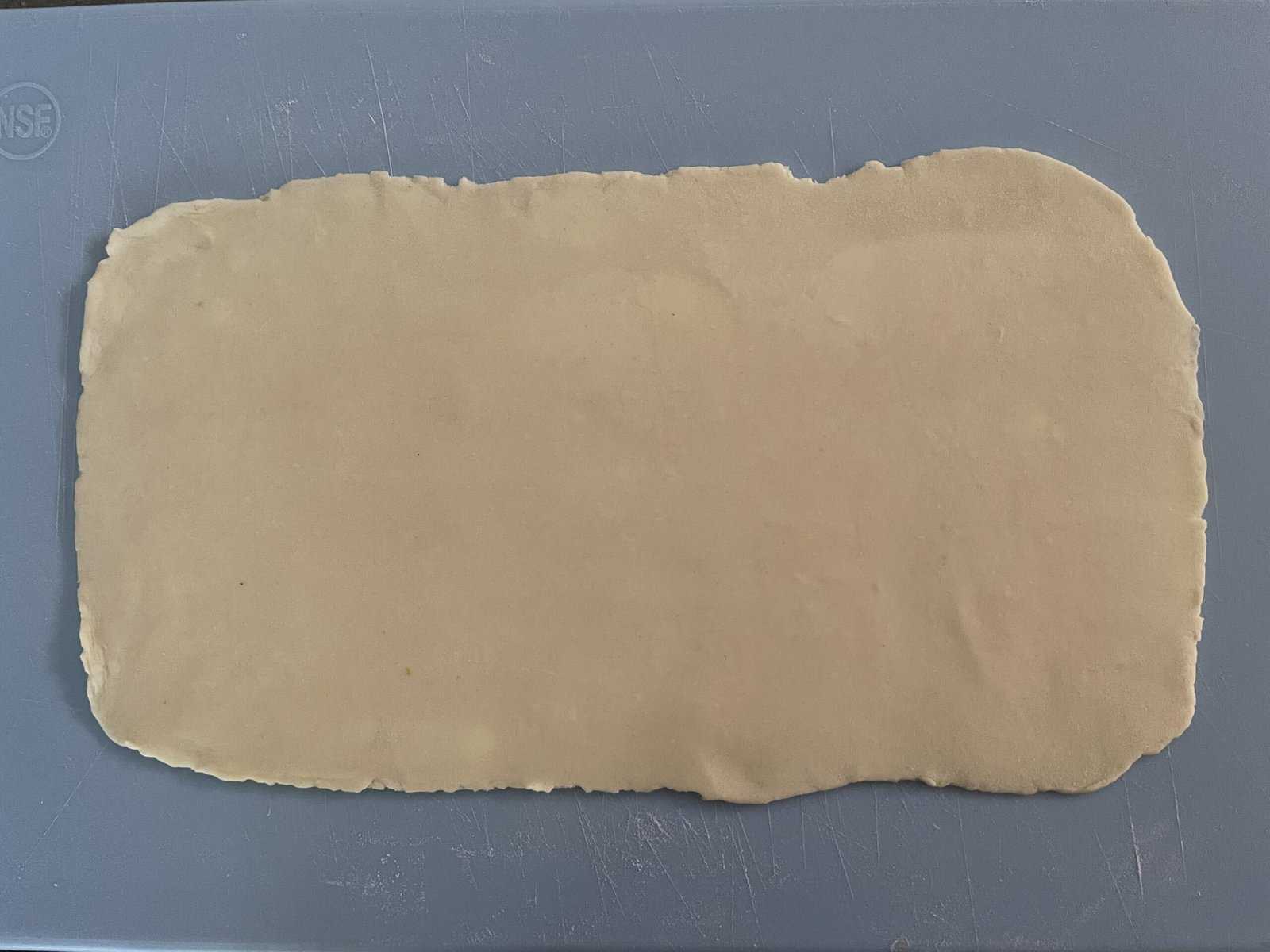 rectangle of pastry dough on a blue cutting board.