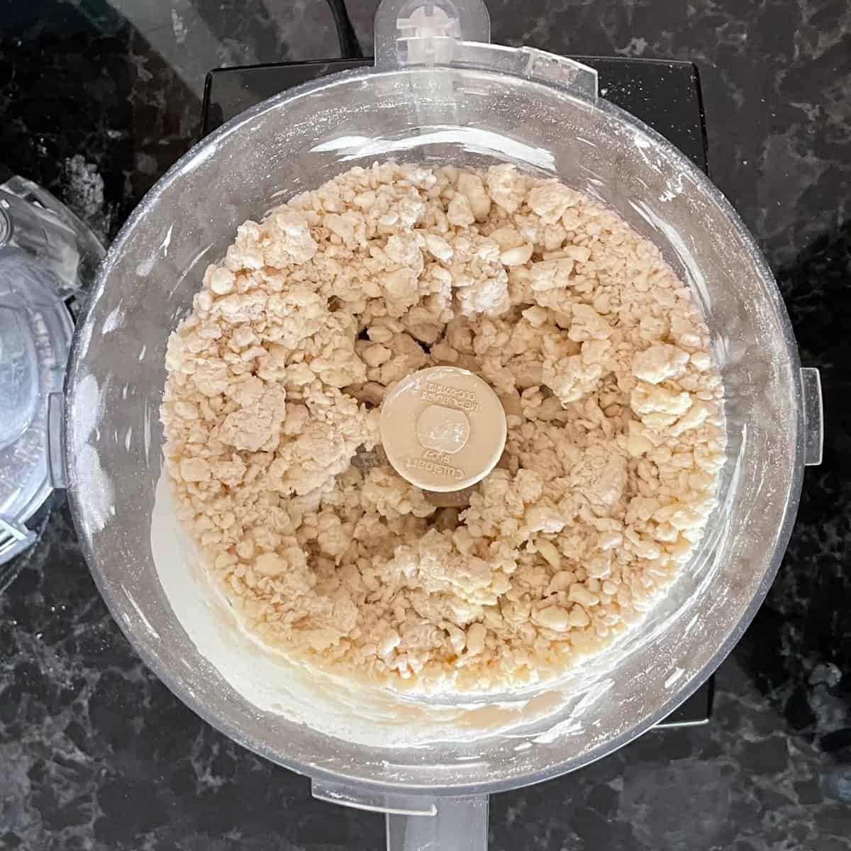 food processor bowl with small bits of clumped butter and flour.