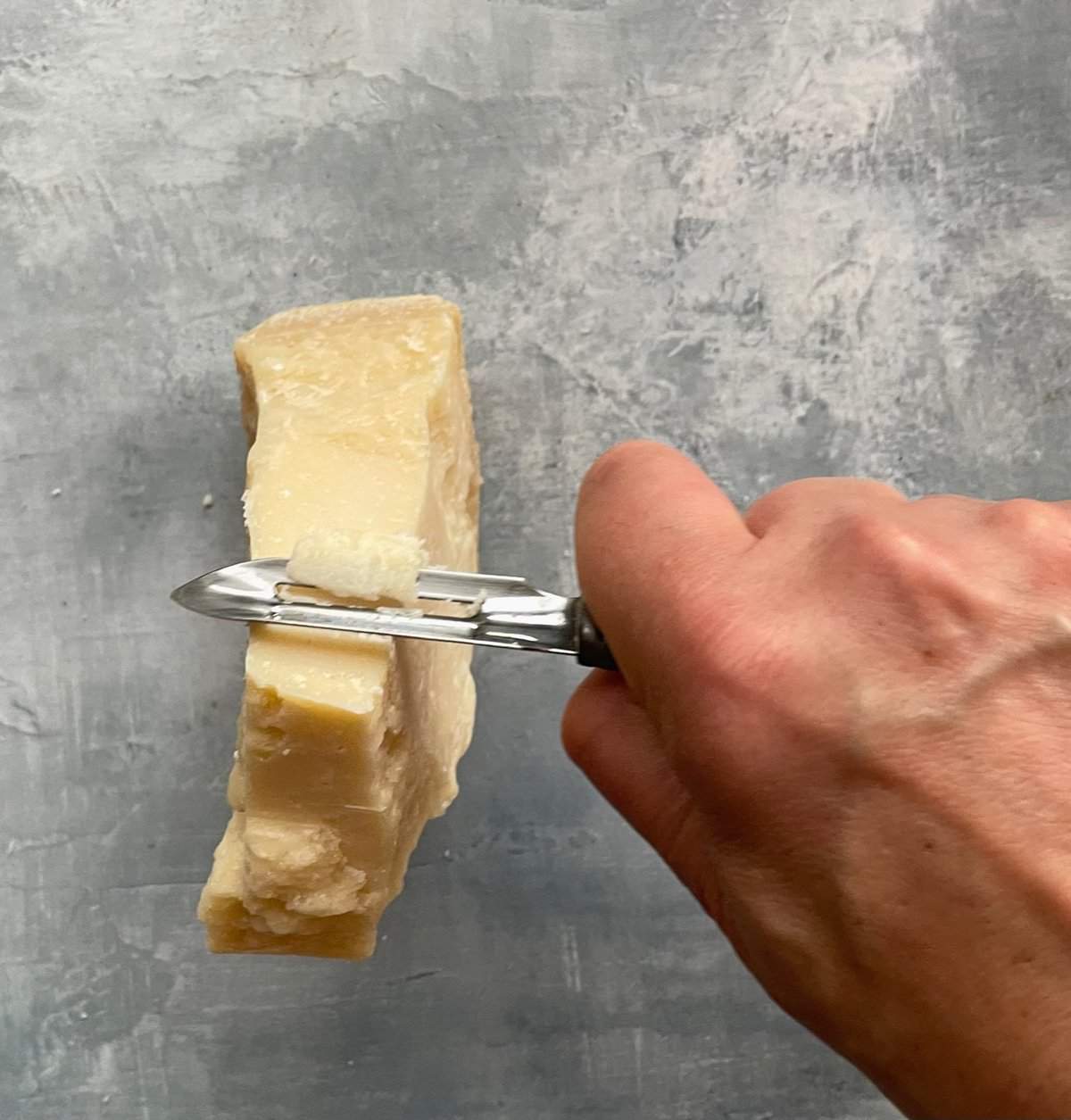 making Parmesan curls with a block of Parmesan and vegetable peeler.