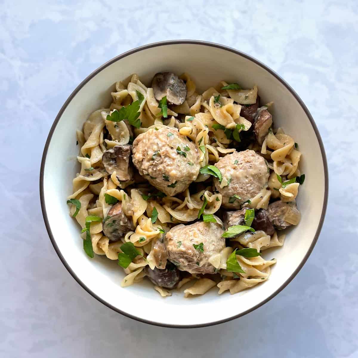 bowl of turkey meatballs over egg noodles, mushrooms, and parsley.    