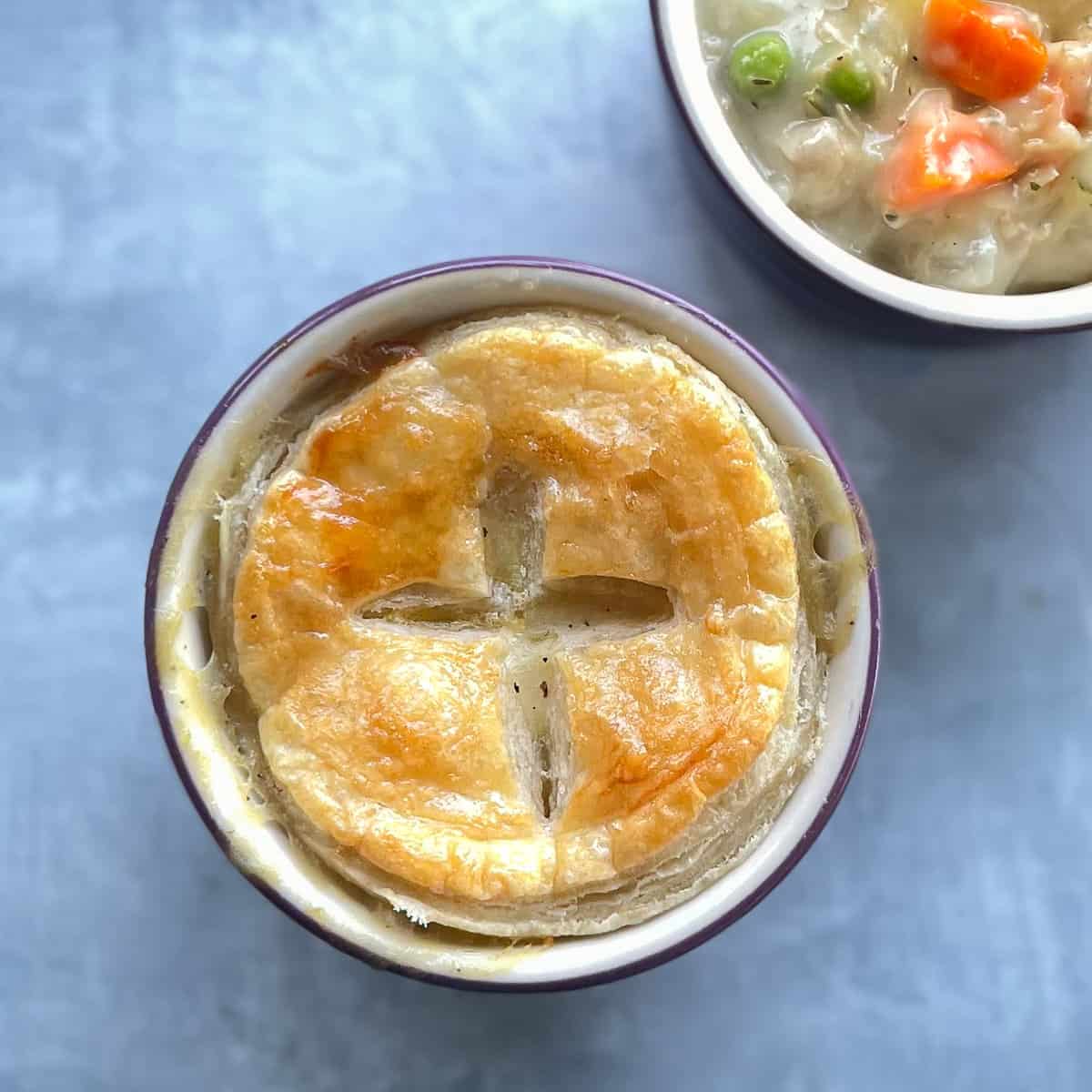 small turkey pot pie with puff pastry on top next to small pot pie without lid.