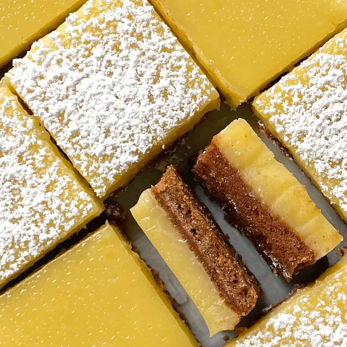 cut lemon squares on an angle with three dusted with powdered sugar and one on its side.