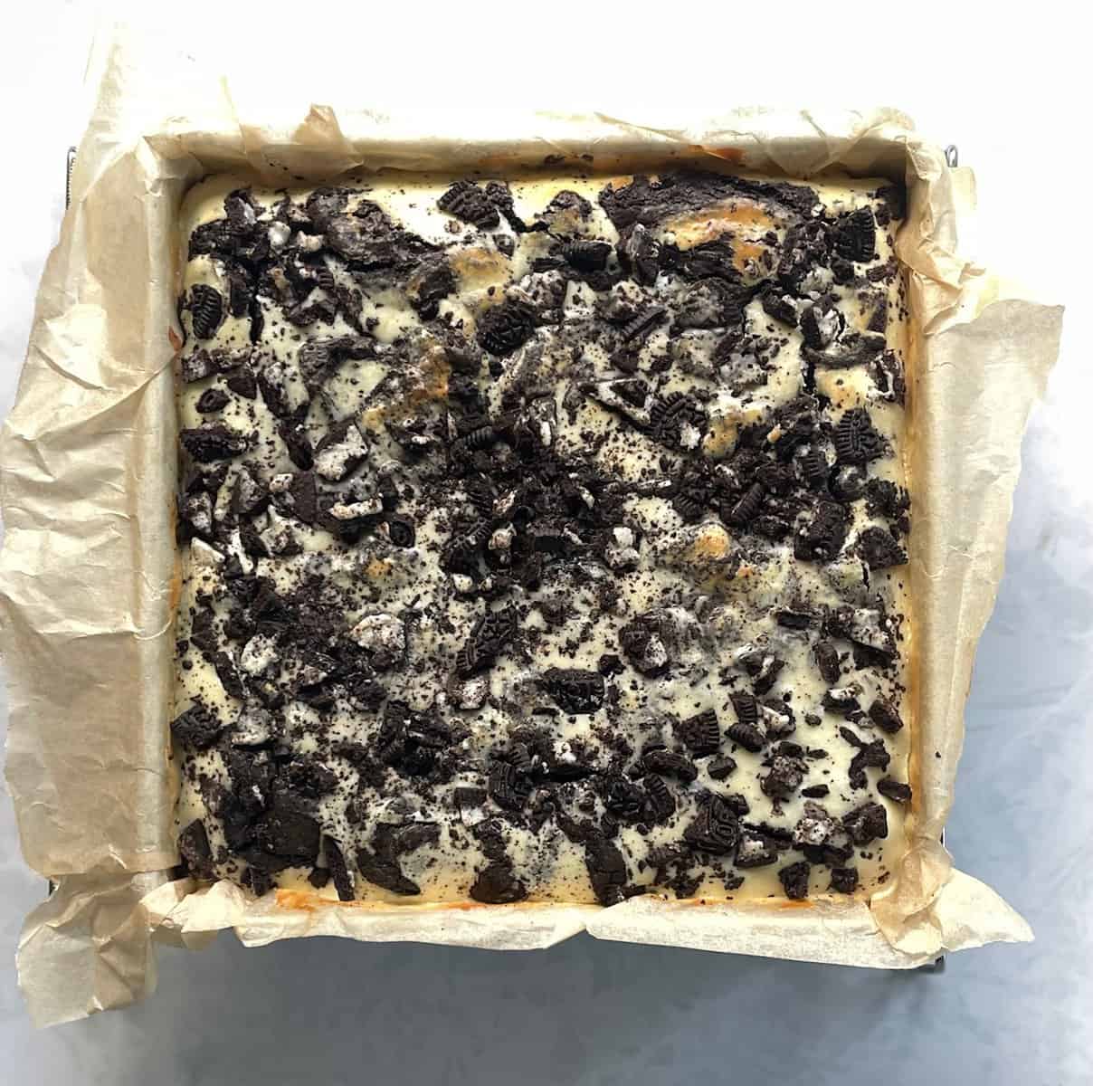parchment lined pan with baked Oreo cheesecake brownies.