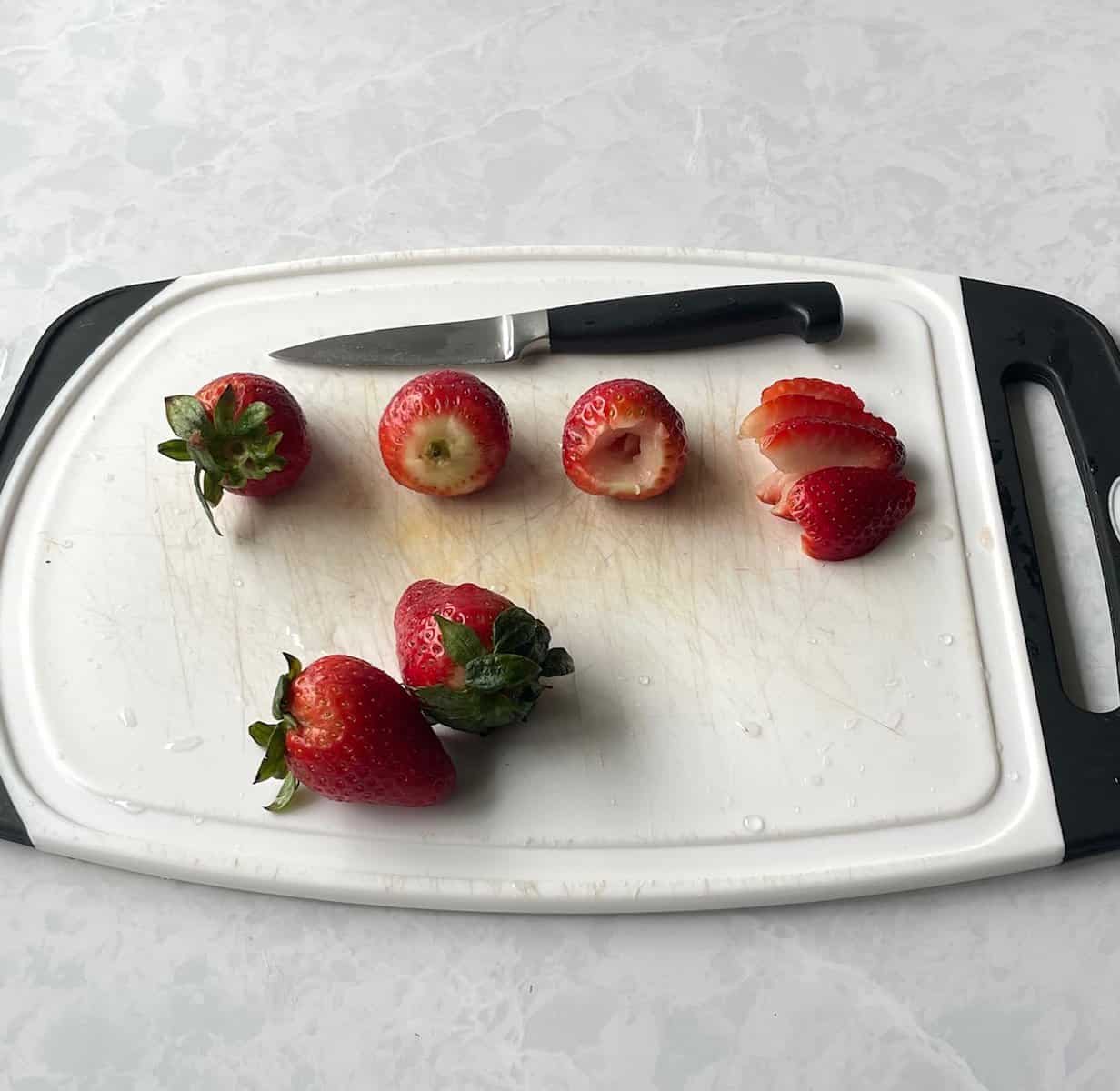 strawberries on a cutting board, illustrating the steps how to hull and slice strawberries.