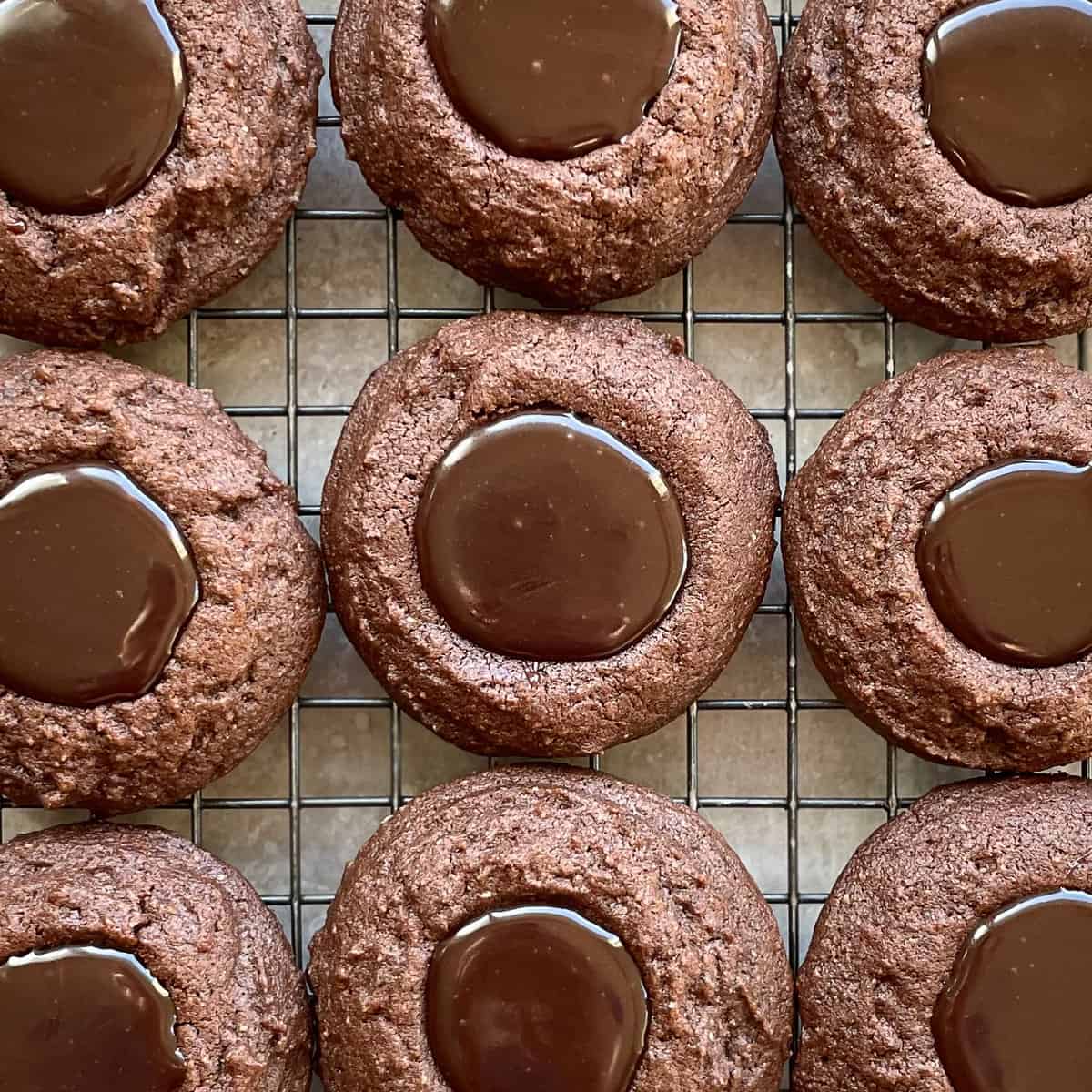 nine brown thumbprint cookies filled with a shiny chocolate brown filling.