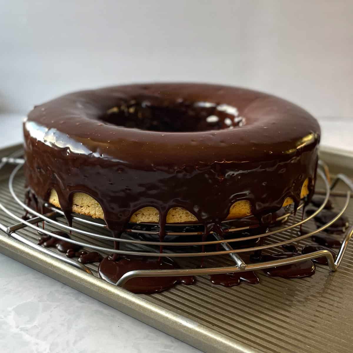 bundt cake dripping with a Nutella ganache on a cooling rack over a baking pan.