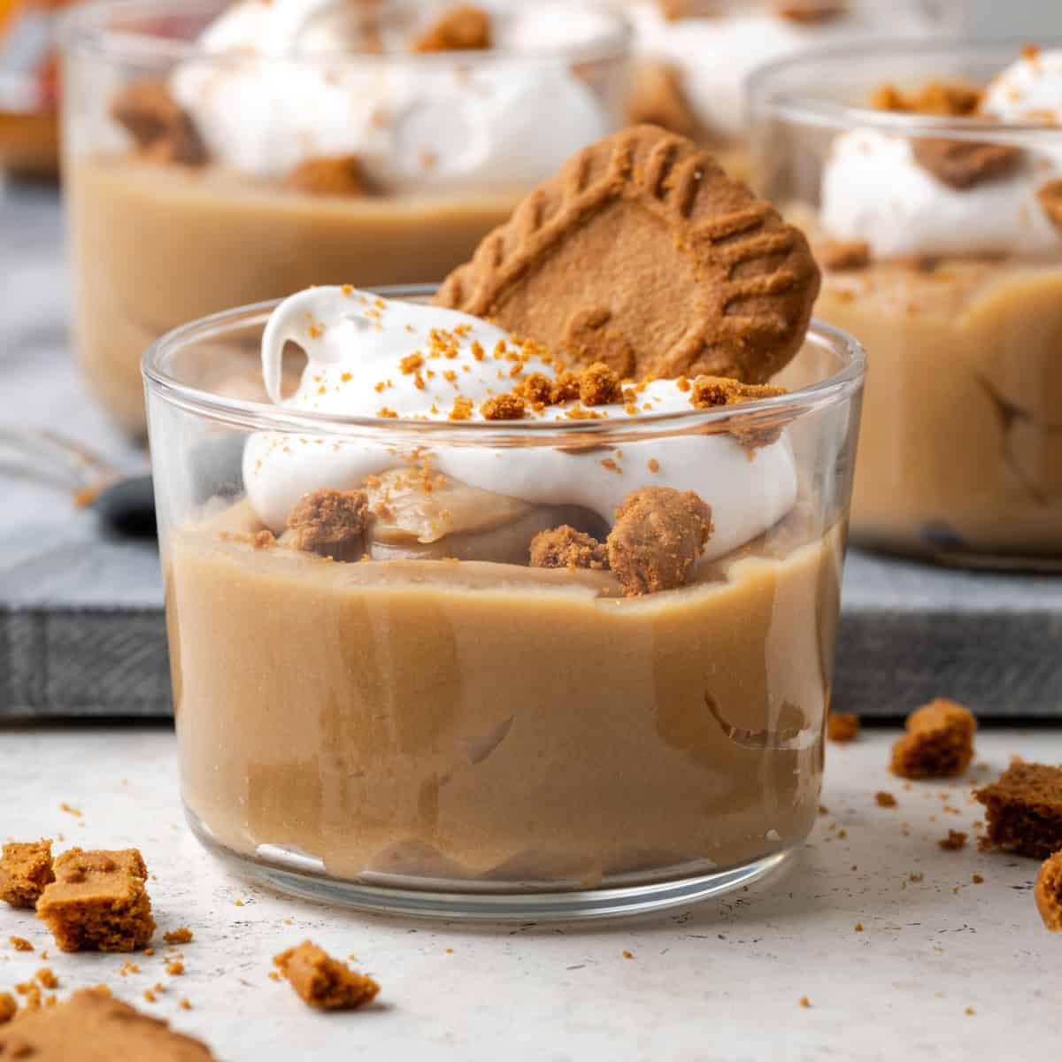 biscoff pudding cups topped with whipped cream and crumbled lotus biscoff cookies. 