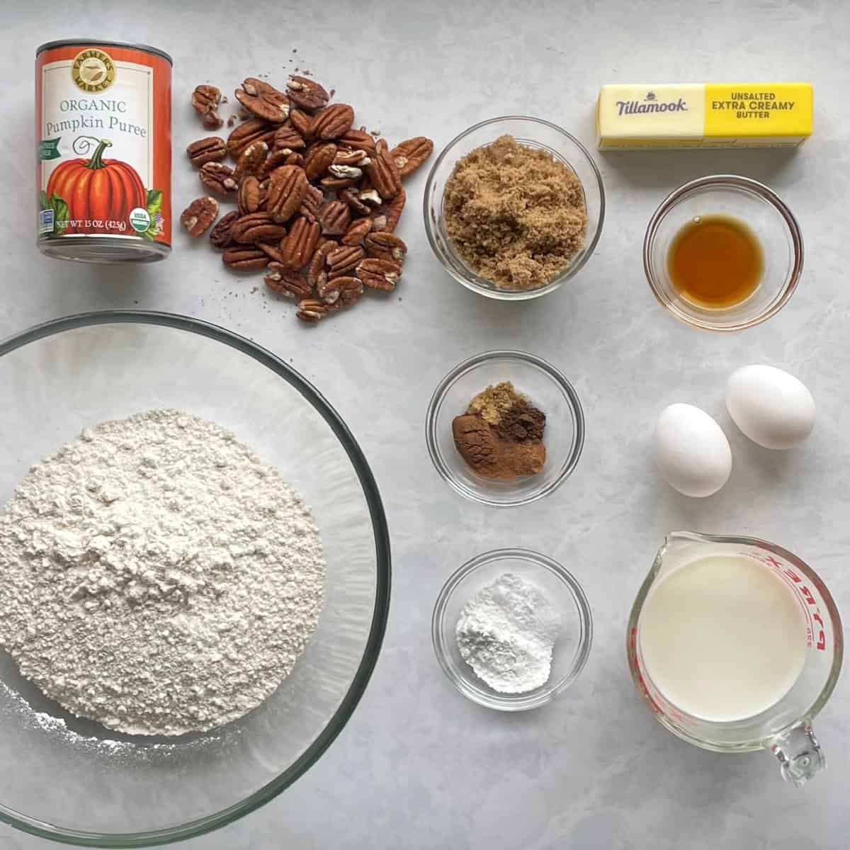 ingredients for pecan pumpkin waffles including can of pumpkin puree, pecans, flour, brown sugar, butter, vanilla, eggs, and milk.