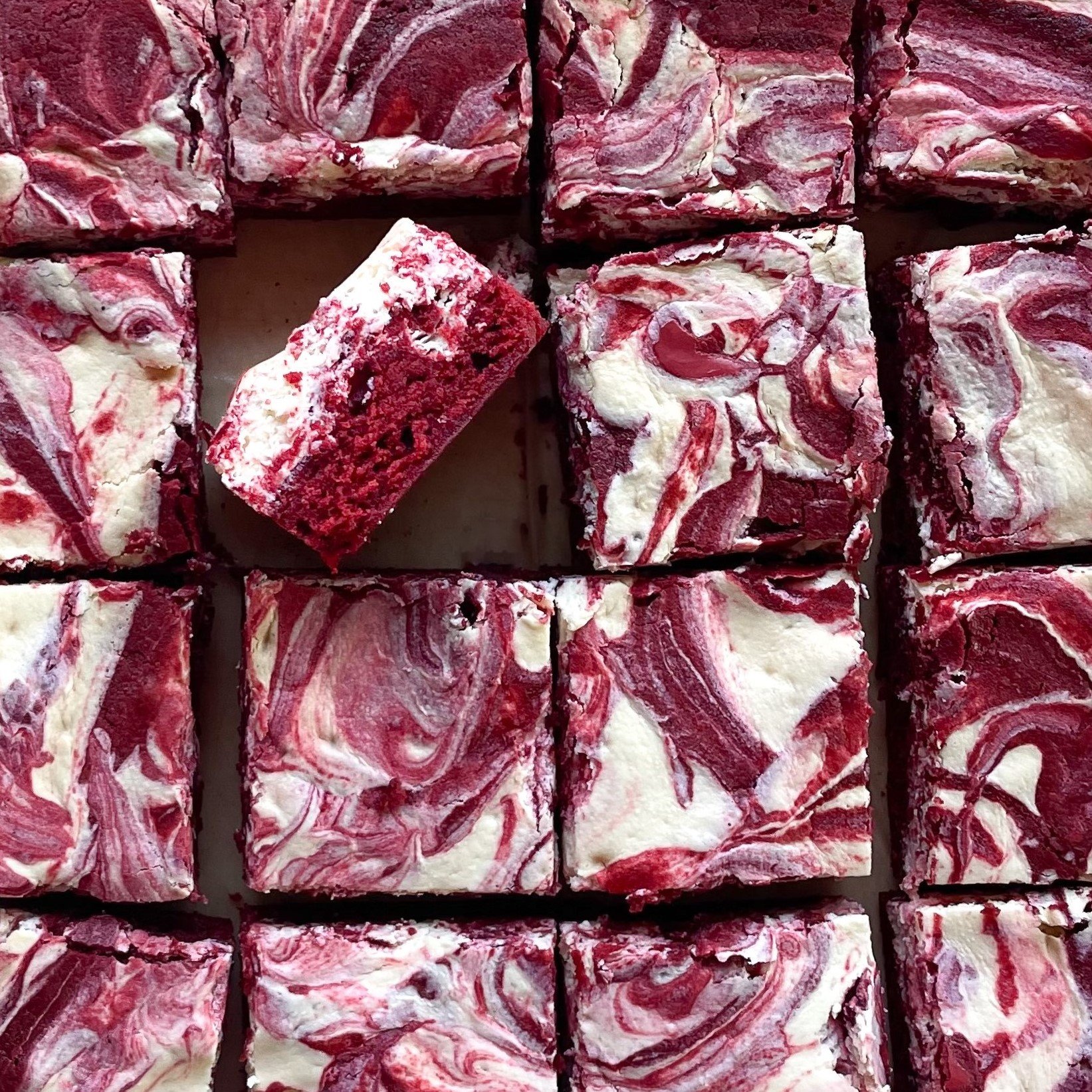 sixteen cut red velvet brownies with one on its side.