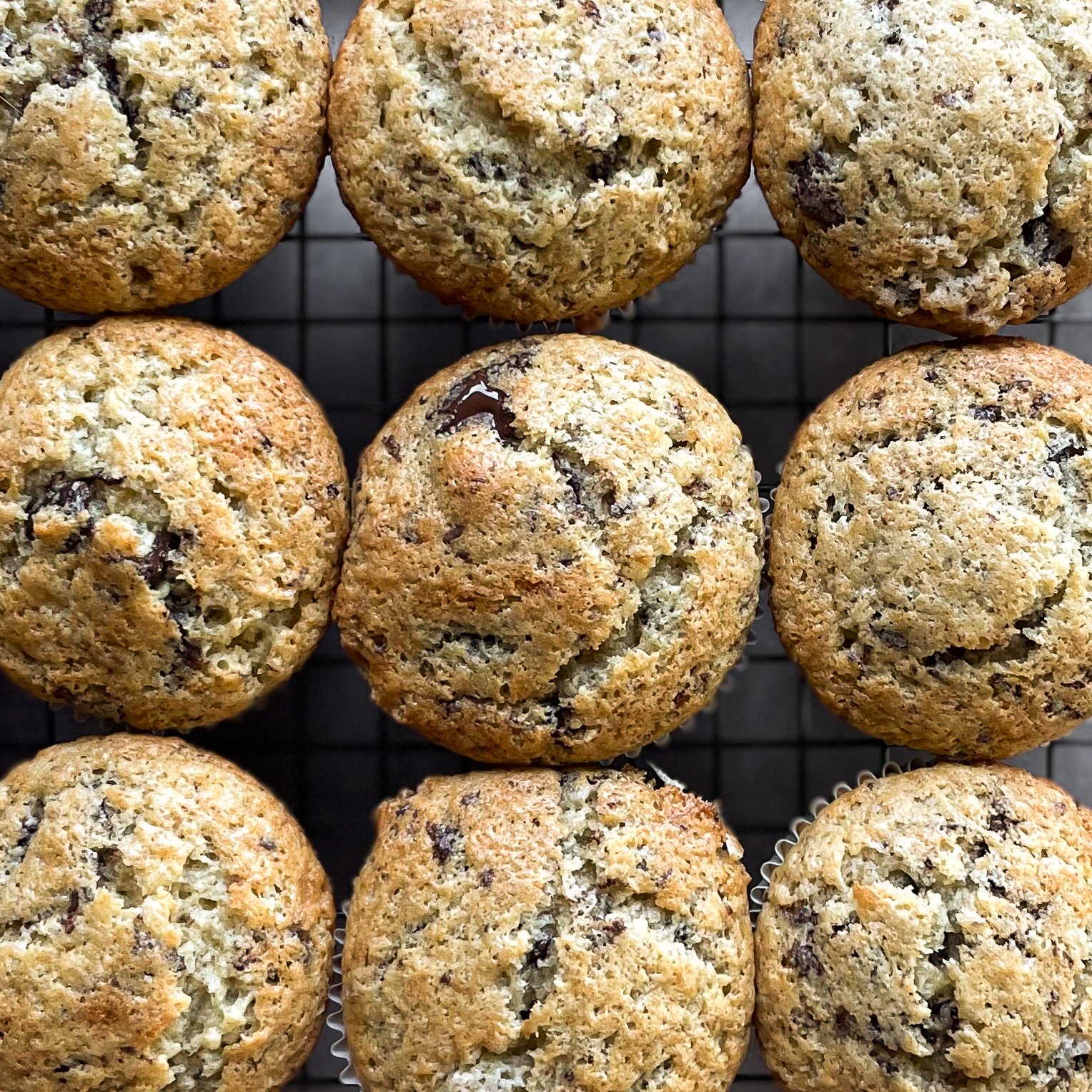 nine banana chocolate chunk muffins on a cooling rack.