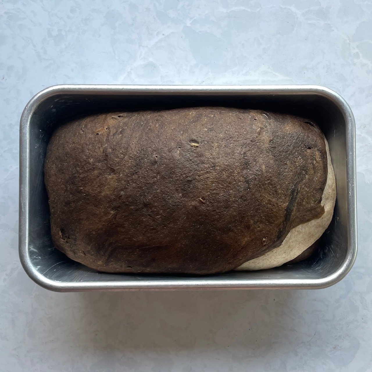 marble rye bread loaf in the loaf pan ready for baking.