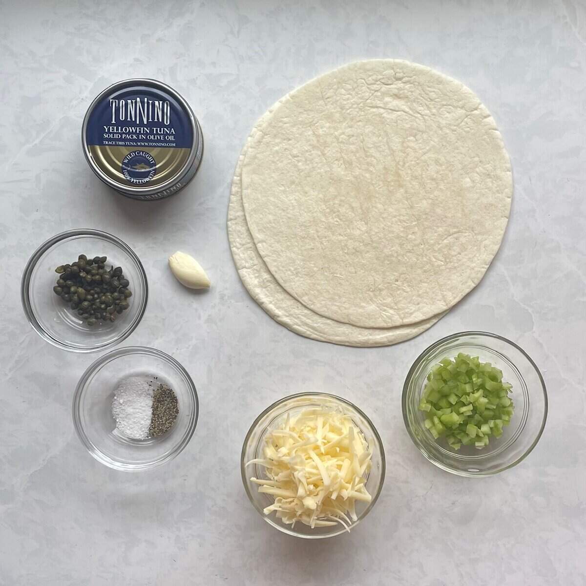 can of tuna, tortillas, garlic, capers, celery, shredded cheese, salt, and pepper.