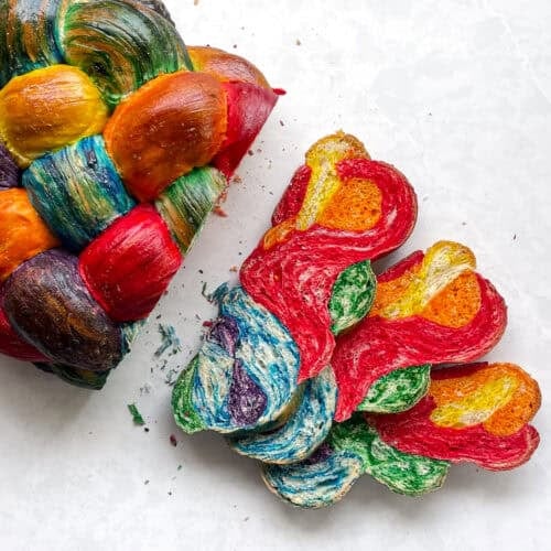 round rainbow challah with three slices cut.