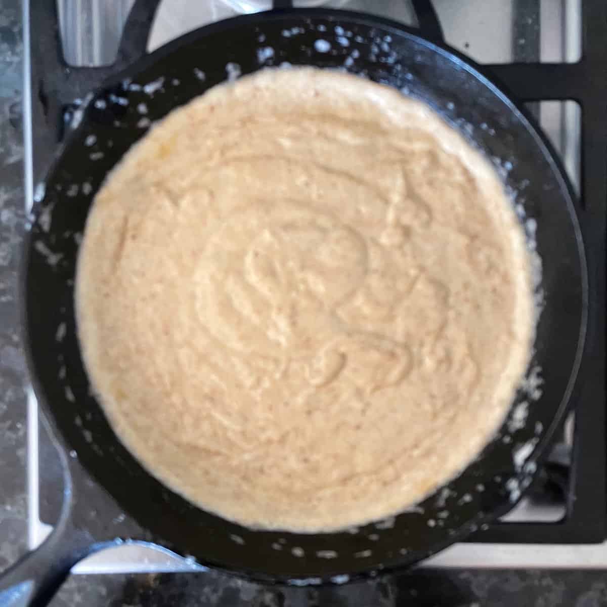 tan colored batter in a cast iron frying pan.