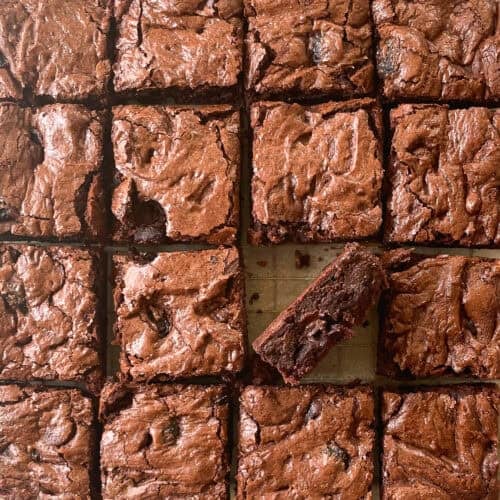 sixteen square cut chocolate brownies with cherries with one on its side.