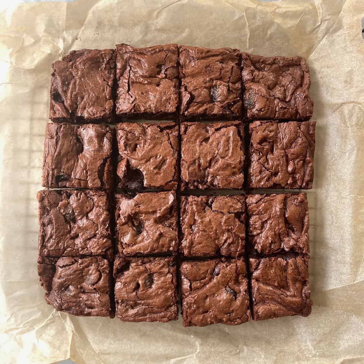 sixteen cut chocolate cherry brownie squares on parchment paper.