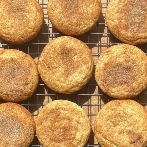 nine snickerdoodle cookies topped with cinnamon sugar on a cooking rack.