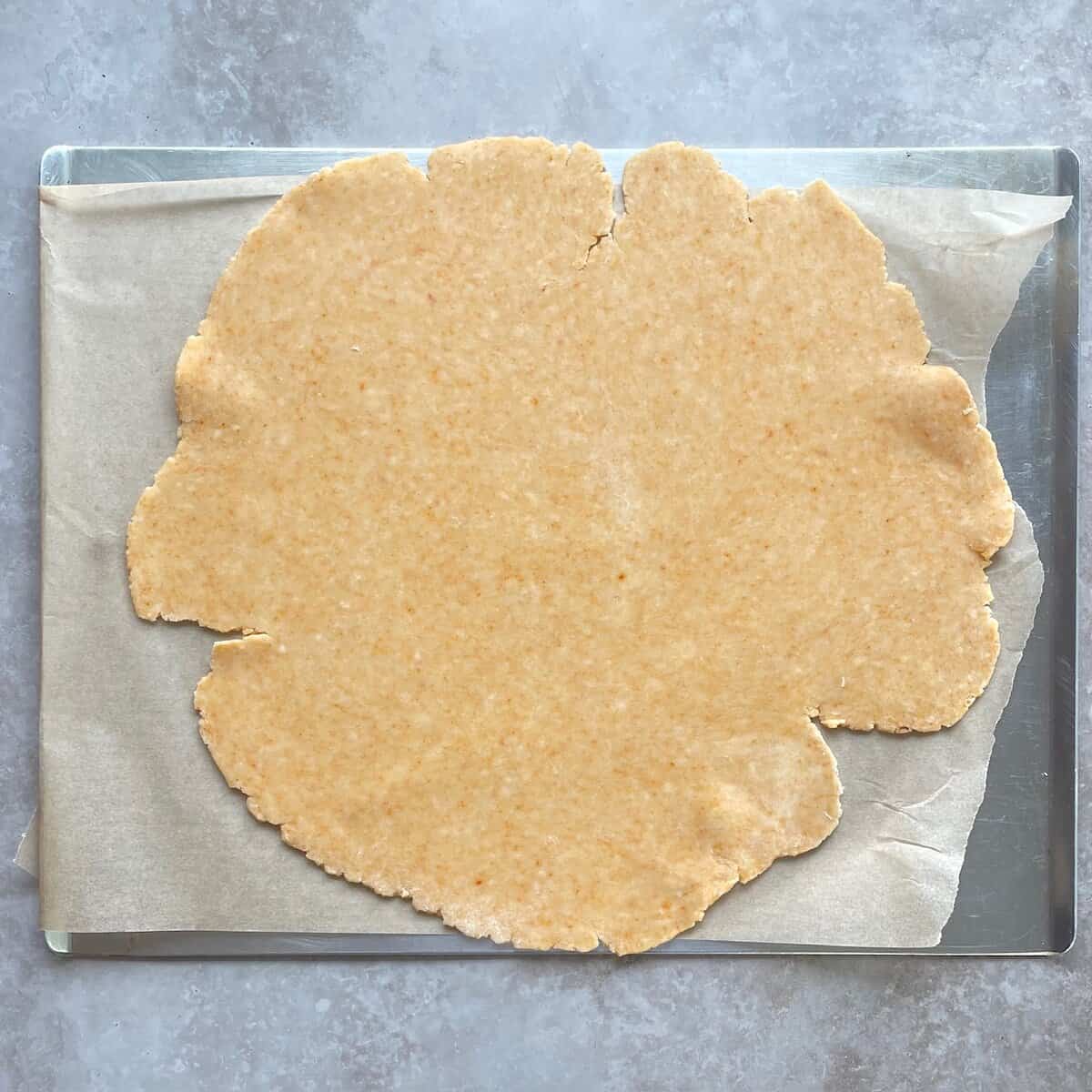 rolled out cheddar cheese pie dough on a parchment-lined baking sheet.