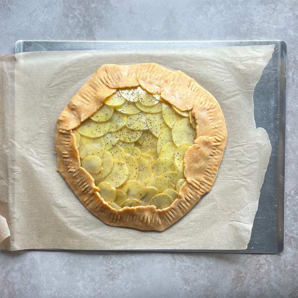 unbaked potato galette on a parchment lined baking sheet.