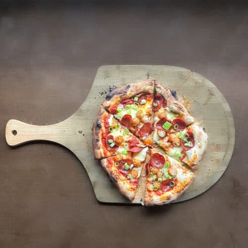 pepperoni green onion and tater tot pizza using same day pizza dough on a pizza peel.