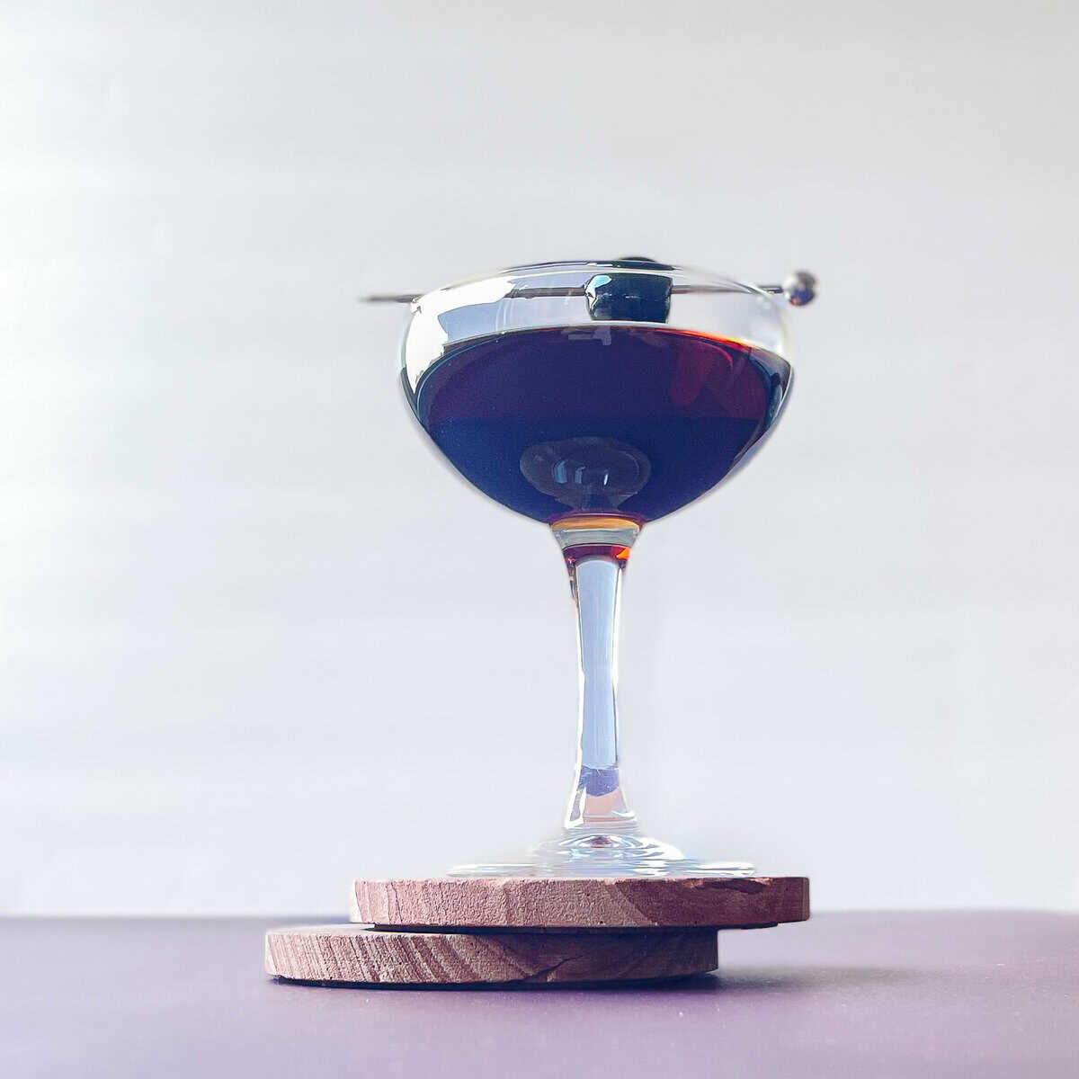 black manhattan in a coupe garnished with luxardo cherry.