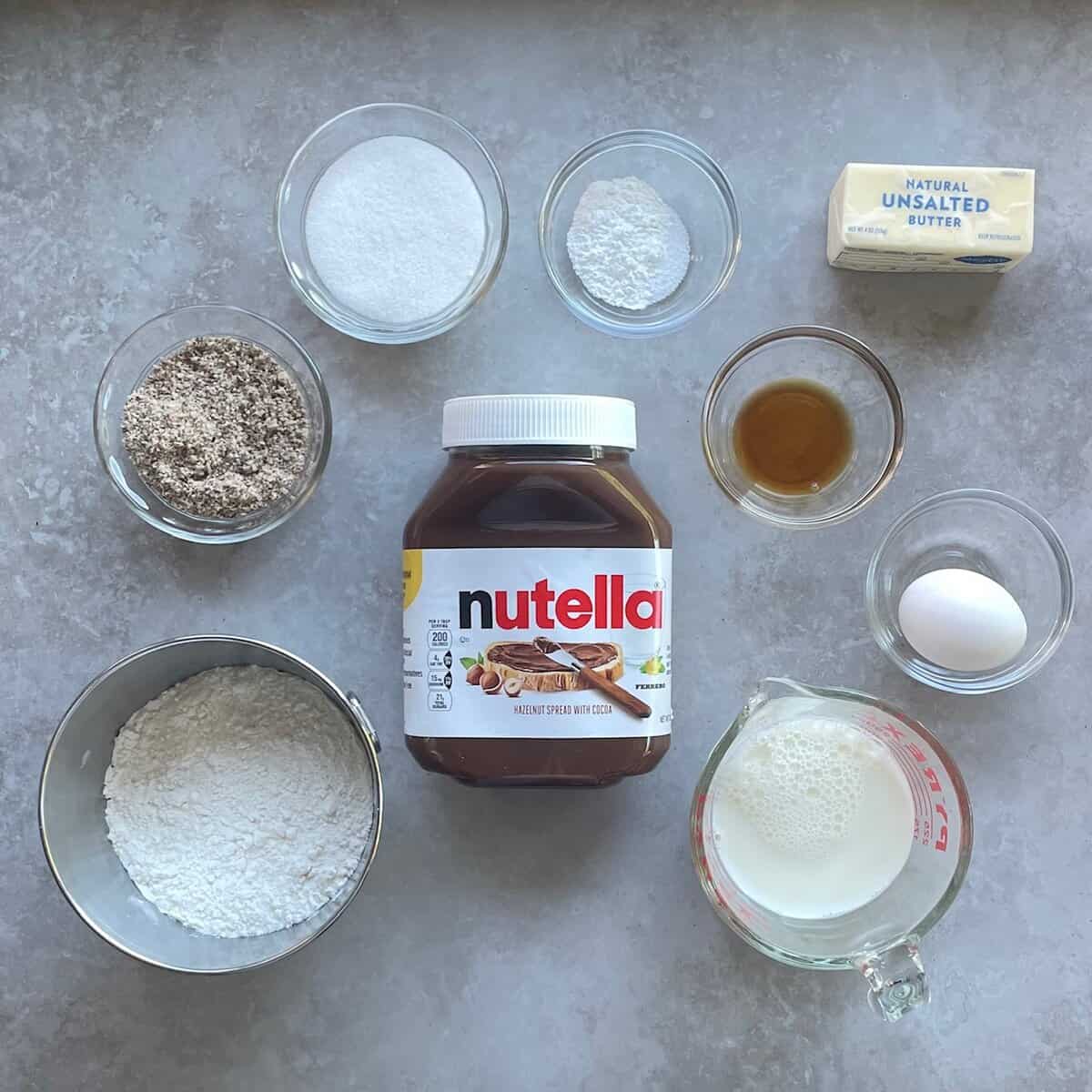 jar of Nutella, flour, hazelnut flour, sugar, egg, milk, and butter.