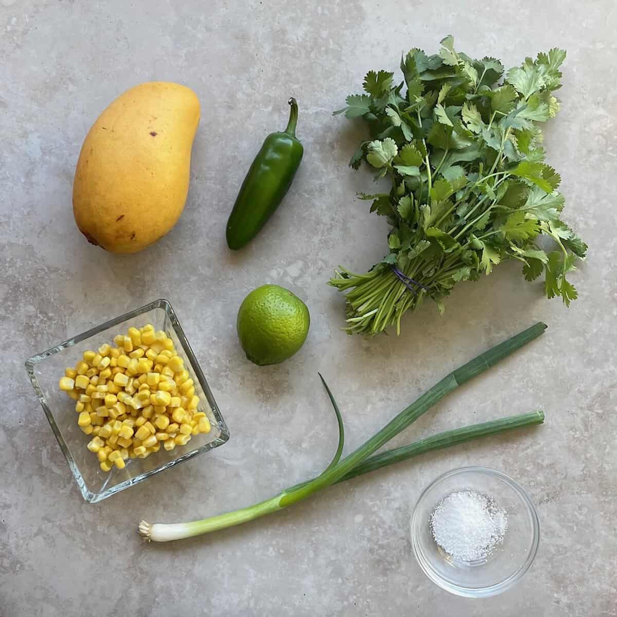 mango, corn kernels, jalapeno, scallion, cilantro, lime, and bowl of salt.