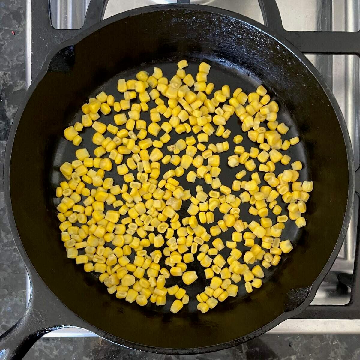 corn kernels in a single layer in cast iron skillet.